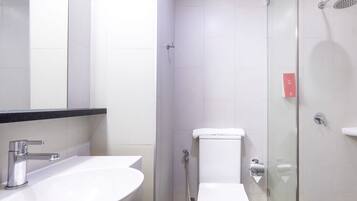 A modern bathroom with a white sink, toilet, and glass-enclosed shower.