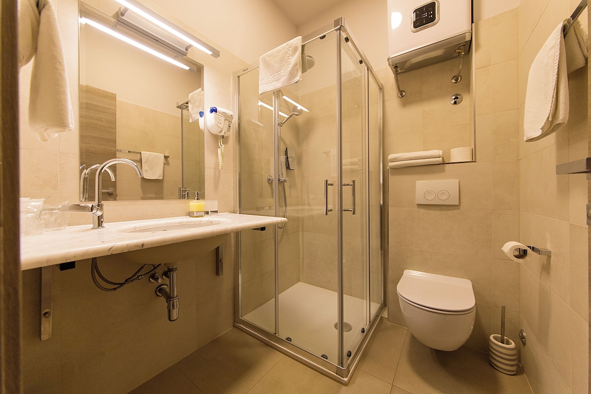 A modern bathroom with a glass-enclosed shower, a toilet, and a sink with a mirror above it.