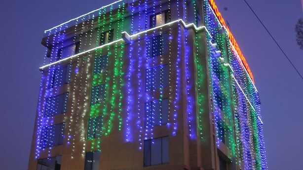 Een gebouw met een moderne gevel, verlicht met kleurrijke lichtslingers.