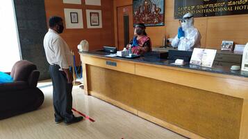 A hotel reception area with a wooden reception desk, a framed certificate, and a sign for Rosewood International Hotel.