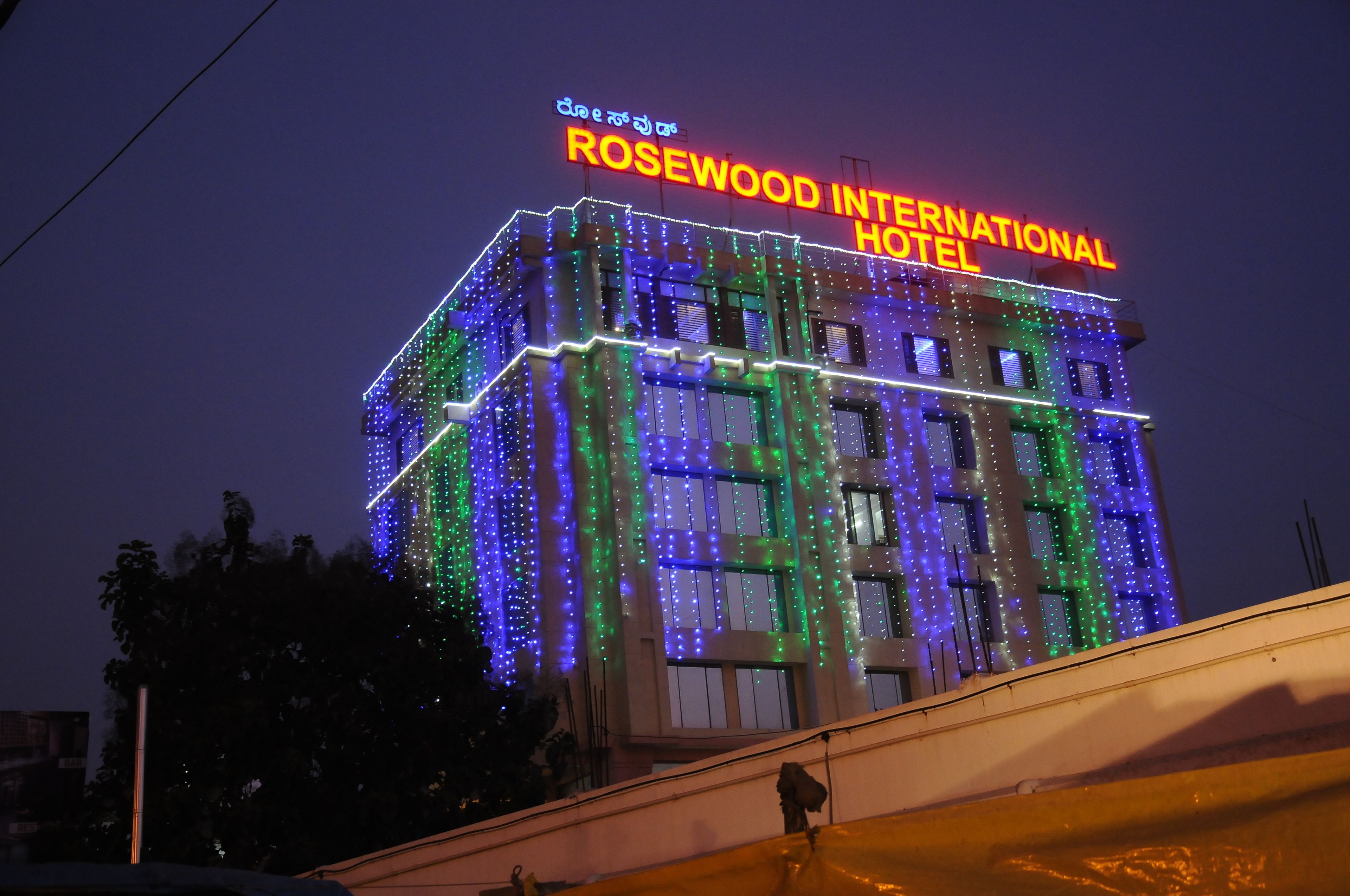 The Rosewood International Hotel with a sign in a foreign language, surrounded by colorful lights.