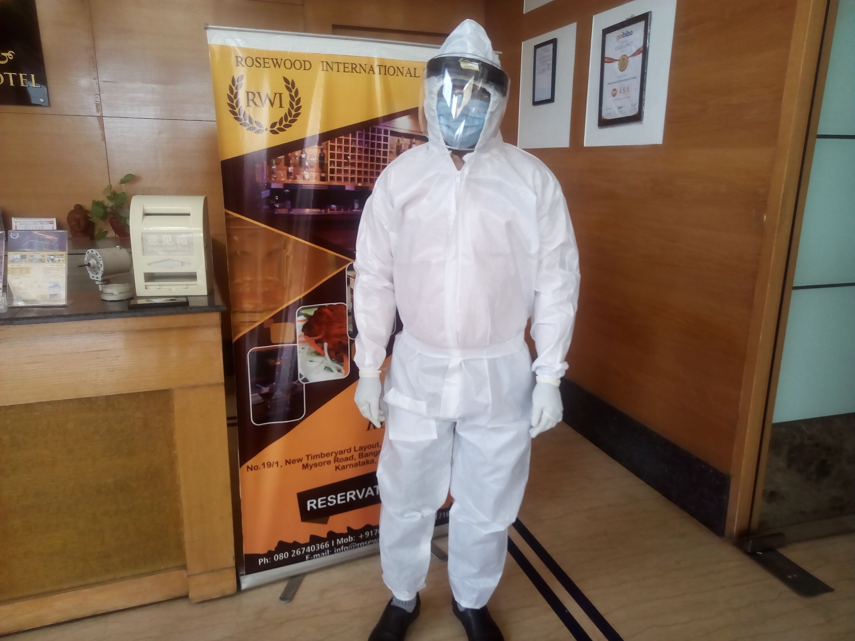 A person in full protective gear standing in front of a hotel reception area.