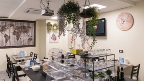 A buffet setup with clear glass containers, a clock on the wall, and a world map artwork. - Rooms Boutique Carducci (Trieste)