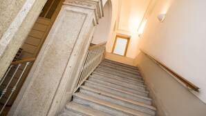 A staircase with stone steps and a wooden handrail, leading to an upper floor. - Rooms Boutique Carducci (Trieste)