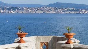 A coastal cityscape with a view of the sea and mountains in the background. - Rooms Boutique Carducci (Trieste)