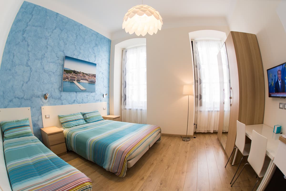 Habitación de hotel con dos camas, un escritorio, un televisor y una ventana con cortinas.