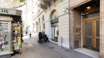 A street with a kiosk selling postcards and a building with a large wooden door.