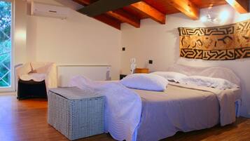 Een slaapkamer met een bed, een rieten stoel, een wandtapijt en een raam.