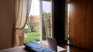 Une chambre avec un lit, une fenêtre avec des rideaux et une vue sur un jardin.