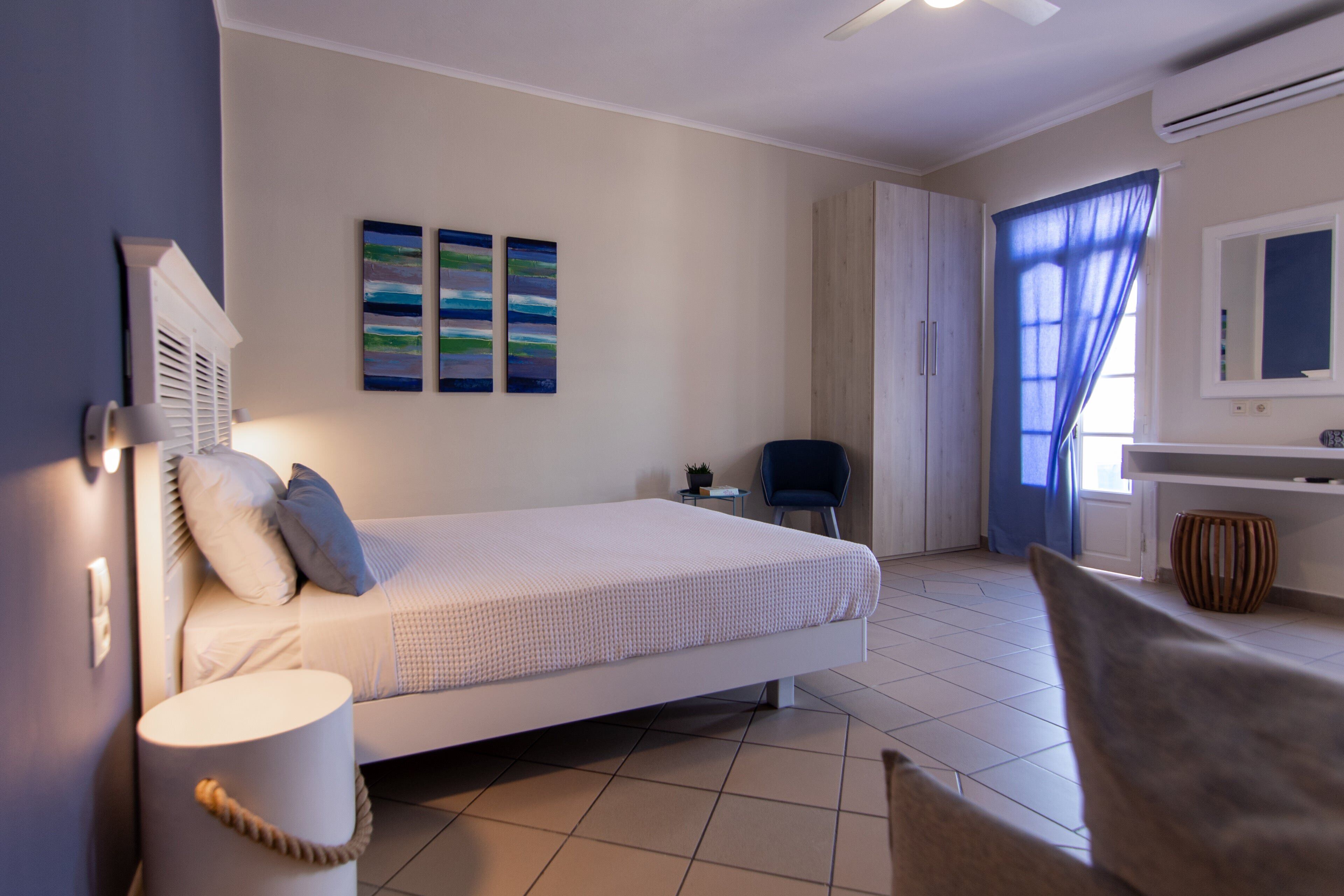 A bedroom with a bed, bedside table, lamp, and artwork on the wall.