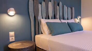 A neatly made bed with a headboard made of wooden planks, a bedside lamp, and a textured round stool.