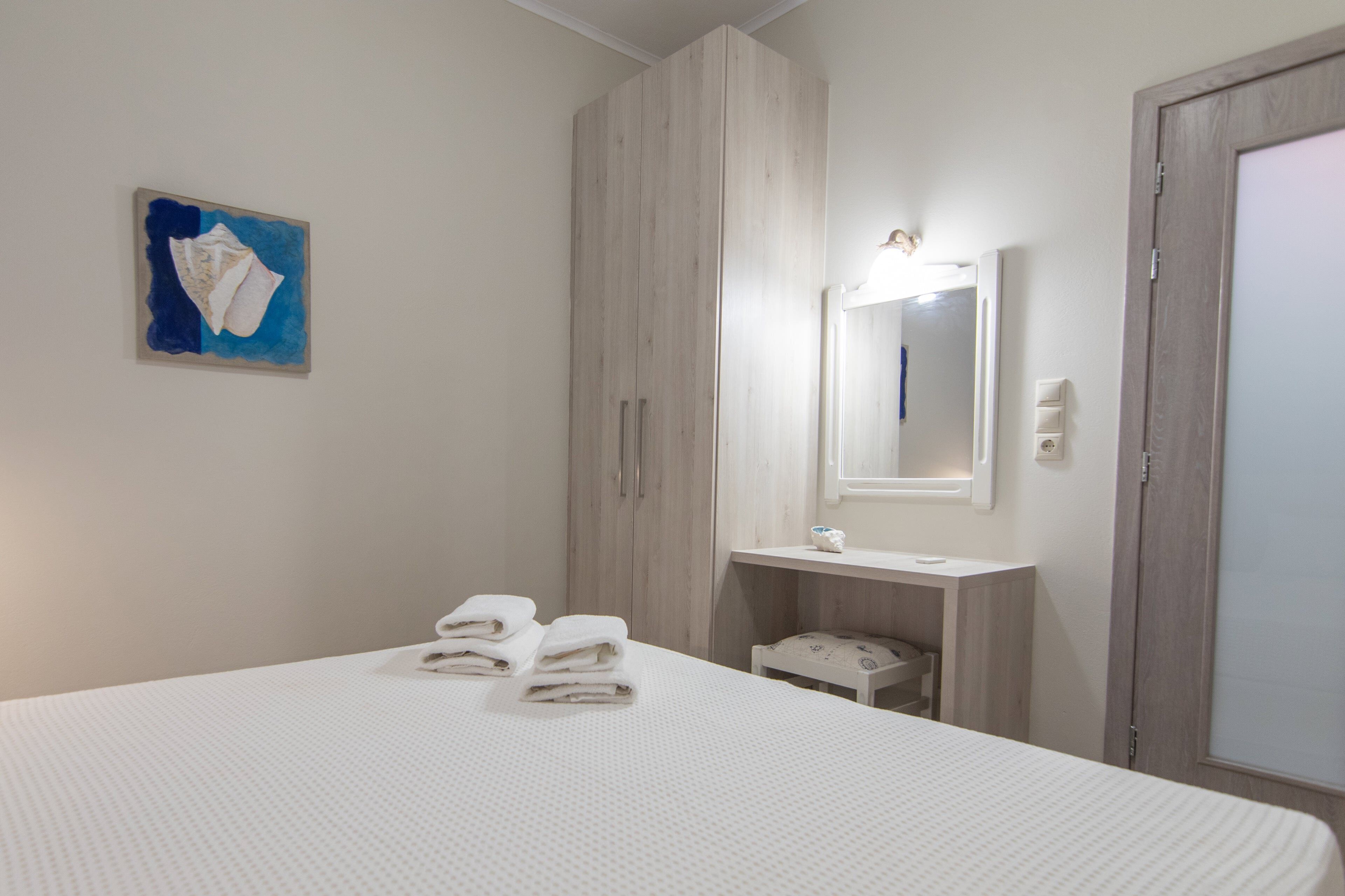 A bedroom with a bed, a nightstand, a mirror, and a wall-mounted artwork.
