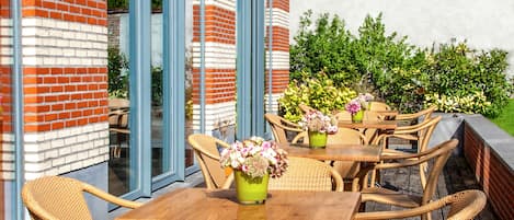 Un patio al aire libre con mobiliario de mimbre y plantas en macetas.