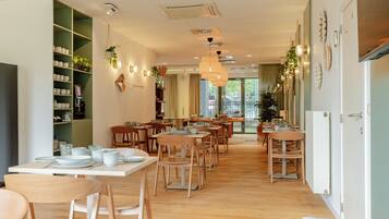 A dining area with multiple tables and chairs, a bookshelf, and decorative wall elements.