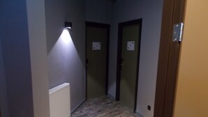 A narrow hallway with patterned flooring, two doors, and a wall-mounted light fixture. - Urban City Centre Hostel (Brussels)