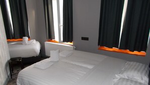 A hotel room with two beds, a wooden floor, and a window with curtains. - Urban City Centre Hostel (Brussels)