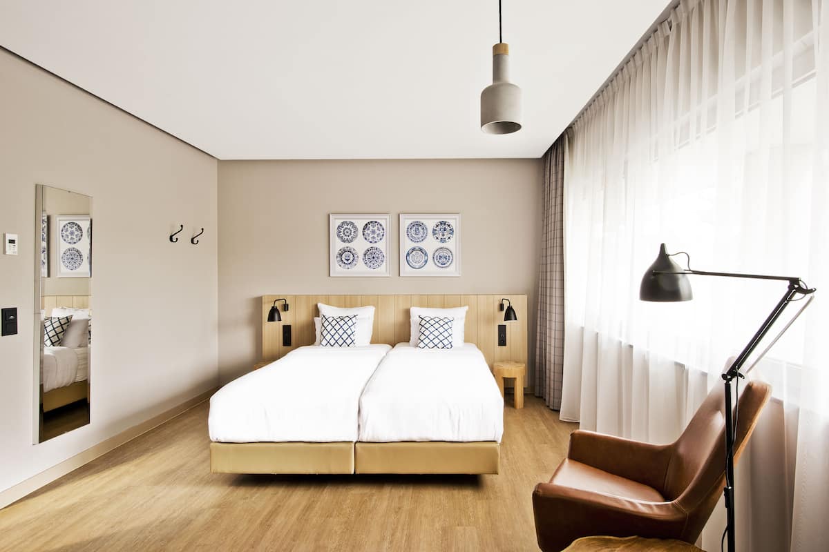 A modern bedroom with a large bed, a chair, a desk, and a lamp.