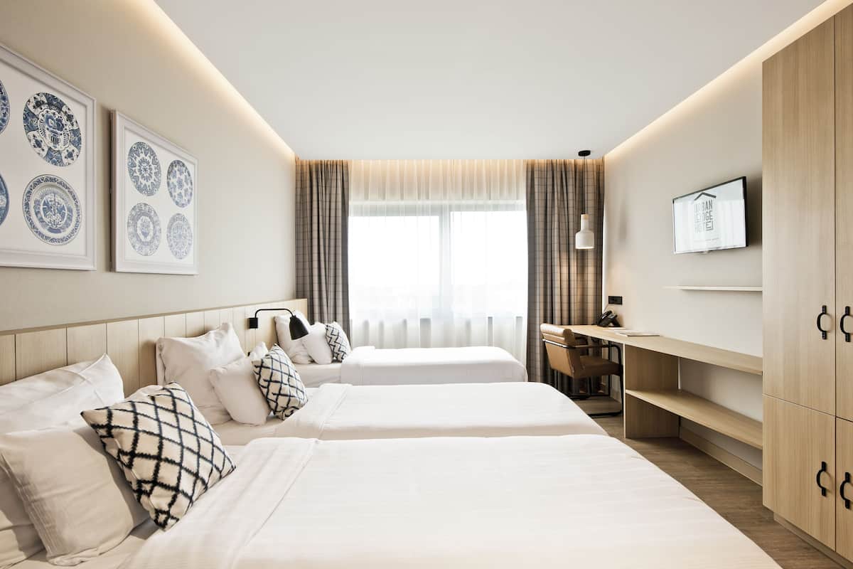 A hotel room with two beds, a desk, a TV, and a wardrobe.