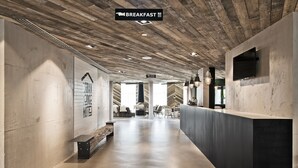 A modern hotel lobby with a wooden ceiling, a reception desk, and a seating area. - Urban Lodge Hotel (Amsterdam)