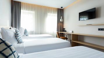 Habitación de hotel con dos camas, un escritorio, una silla, un televisor y una ventana con cortinas.