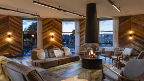 A modern living room with a large fireplace, wooden walls, and a view of the cityscape. - Urban Lodge Hotel (Amsterdam)