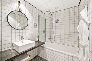 A bathroom with a white sink, a round mirror, a shower, and a bathtub. - Urban Lodge Hotel (Amsterdam)
