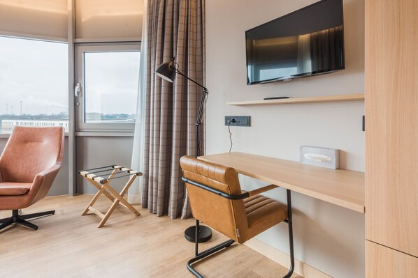 Una habitación moderna con escritorio, silla y televisor montado en la pared.