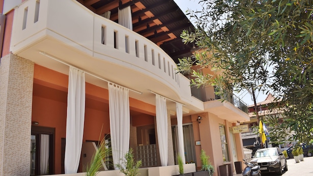 A building with a curved balcony, white curtains, and potted plants. - Kripis Studio Pefkohori (Kassandra)