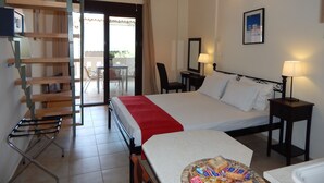 A hotel room with a bed, a desk, a chair, a small table, a lamp, and a balcony with a table and chairs. - Kripis Studio Pefkohori (Kassandra)