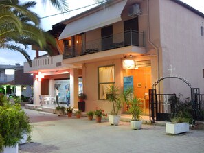 A two-story building with a balcony, potted plants, and a sign indicating it is a real estate office.