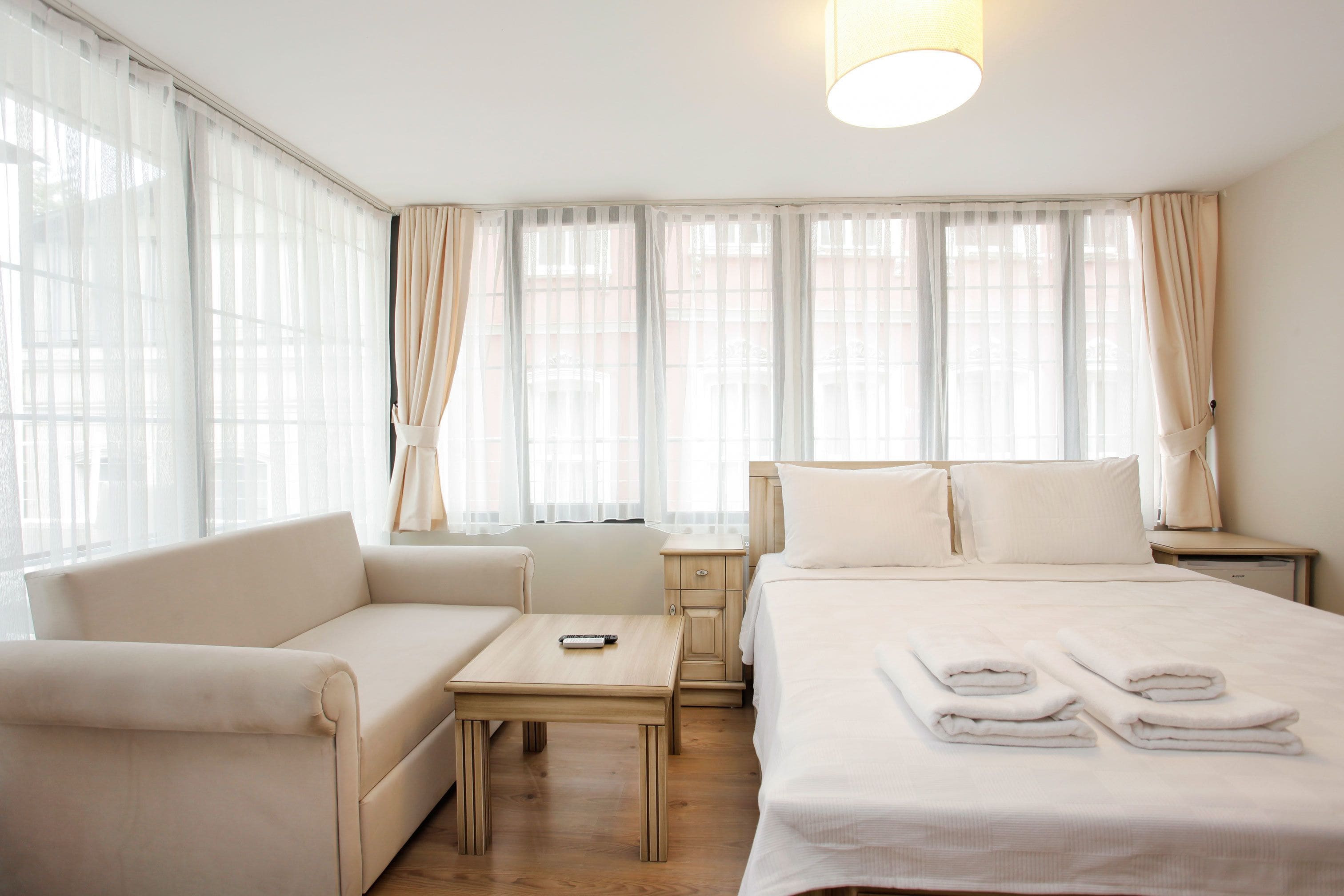 A hotel room with a bed, a sofa, a nightstand, and a table.