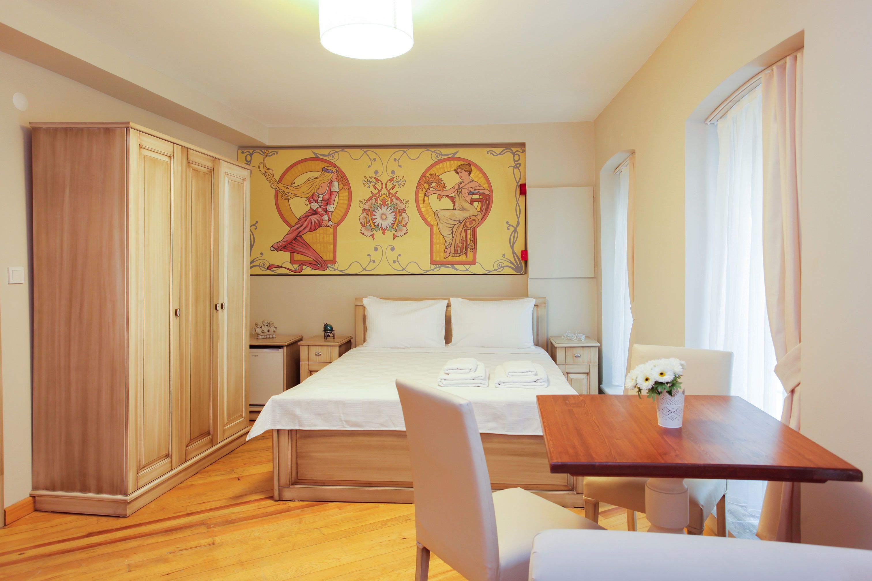 A bedroom with a wooden bed, a nightstand, a desk with a chair, and a wardrobe.