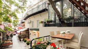A narrow alley with a wooden bench, potted plants, and a table with chairs. - The Loft Istanbul (Istanbul)