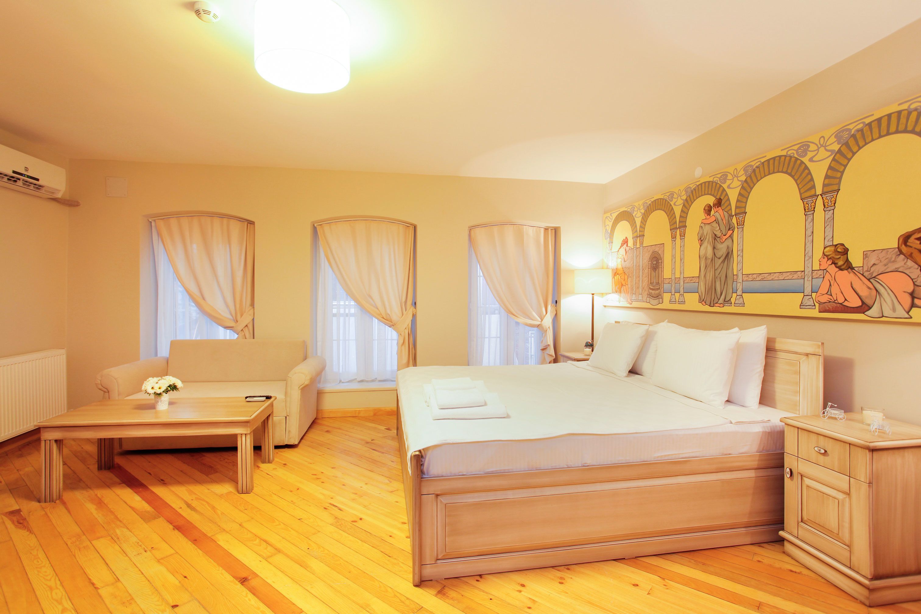 Quarto de hotel com uma cama grande, uma mesa de cabeceira, uma cadeira e um quadro na parede.