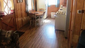 A wooden interior with a dining table, chairs, a refrigerator, and a stove. - Lazy Oaks Resort (Lakeside)