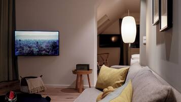 Een moderne woonkamer met een bank, een televisie, een bijzettafeltje en een lamp.