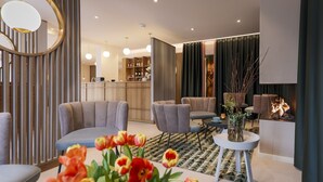 A modern living room with a sofa, armchairs, a coffee table, and a fireplace. - Hotel Astra Maris  (Büsum)