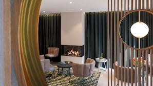 A modern living room with a fireplace, comfortable seating, and a decorative partition. - Hotel Astra Maris  (Büsum)