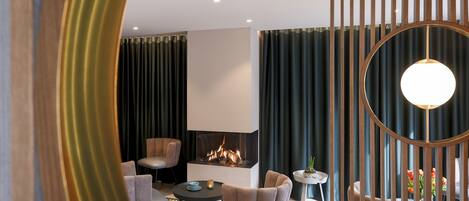 Un salon moderne doté d’une cheminée, de sièges confortables et d’une cloison décorative.