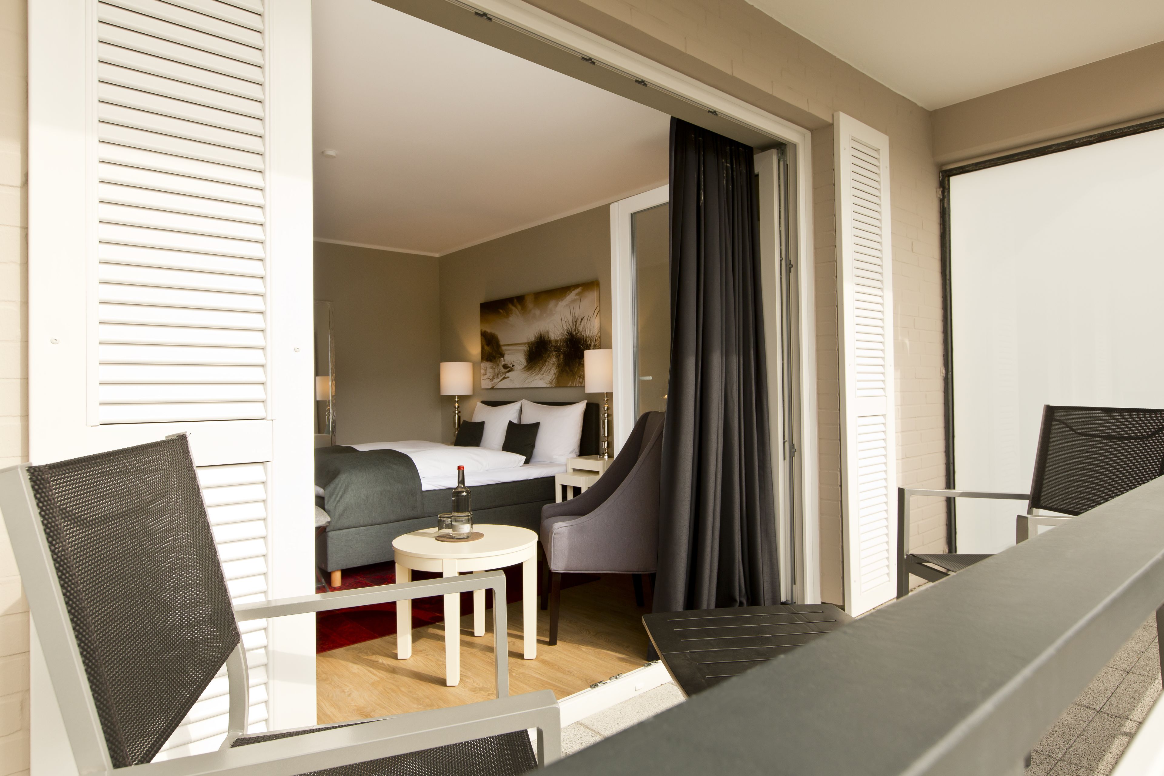 Habitación de hotel con cama, escritorio, silla y vistas al exterior.