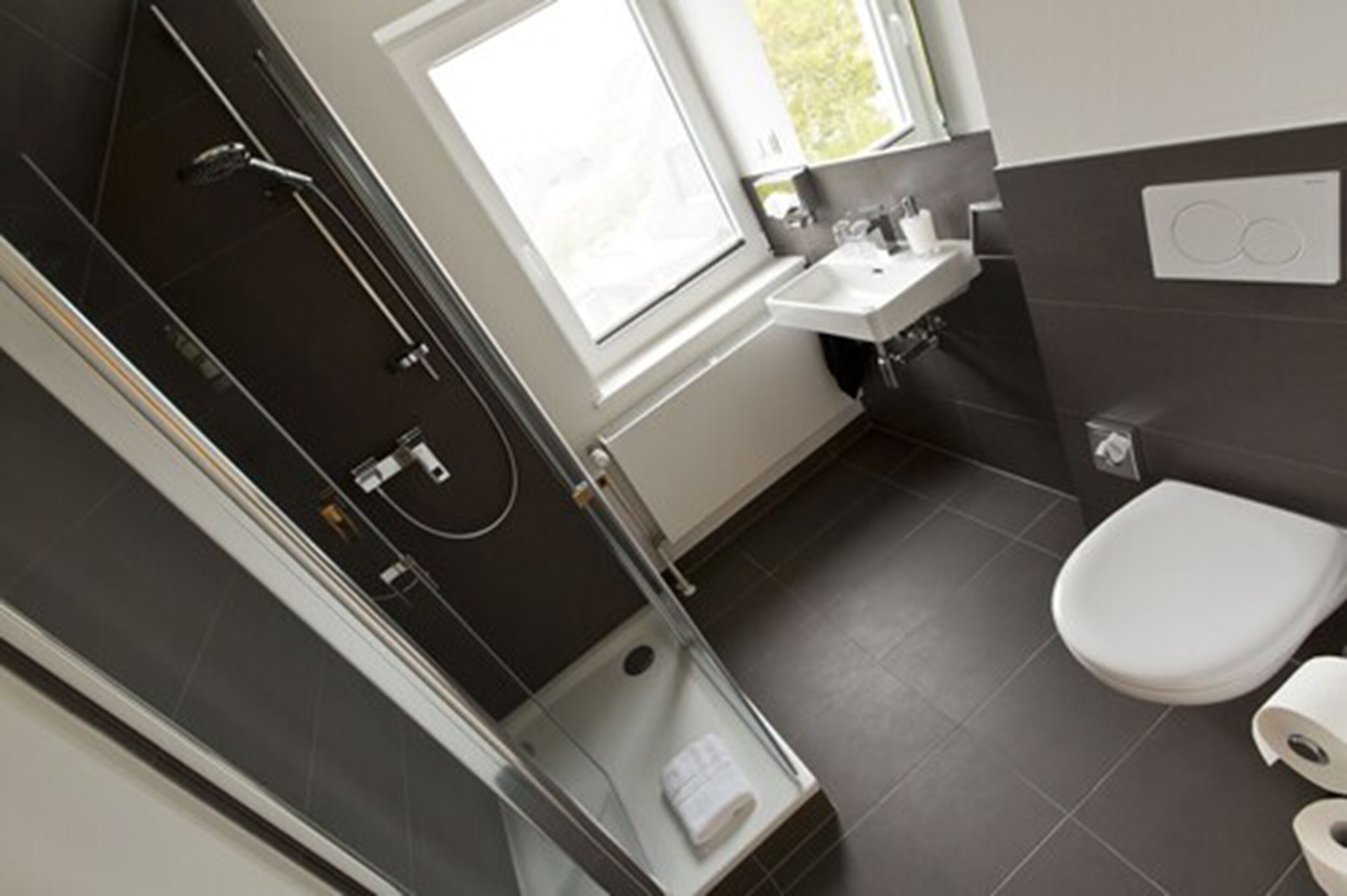 A modern bathroom with a glass shower enclosure, a toilet, and a sink.