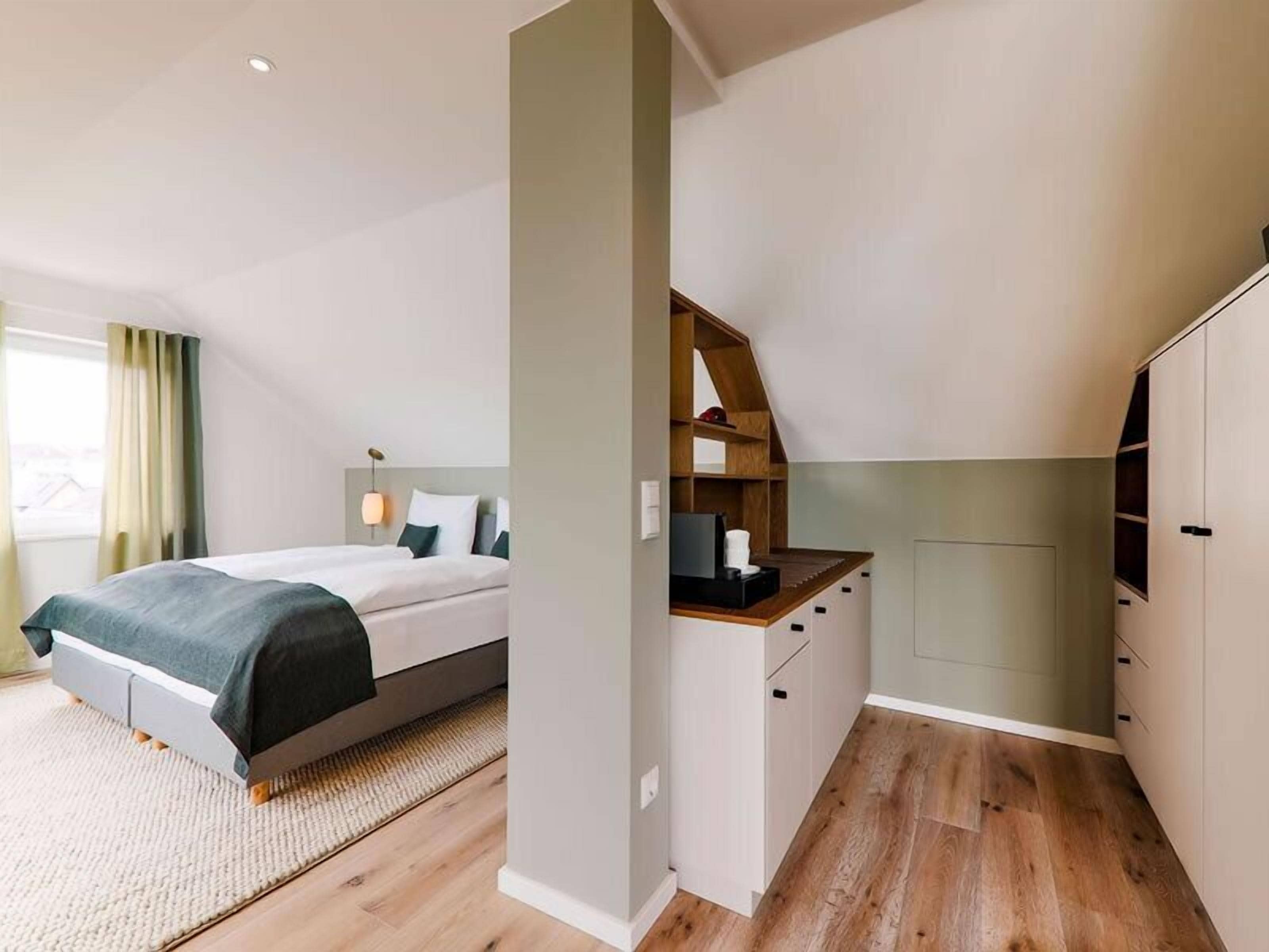 A bedroom with a bed, bedside table, and a small desk area with a chair.