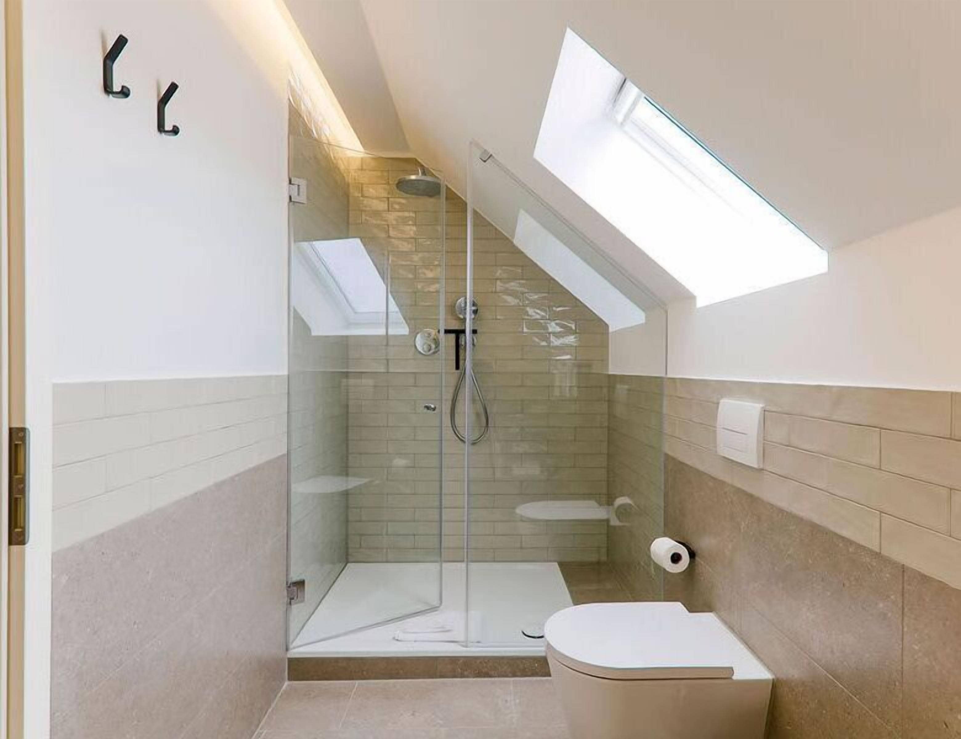 Un baño moderno con ducha de vidrio, tragaluz y retrete.