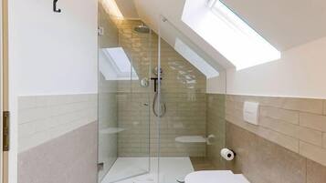 Un baño moderno con ducha de vidrio, tragaluz y retrete.