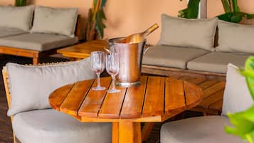 A wooden table with two chairs, a metal pitcher, and two glasses.