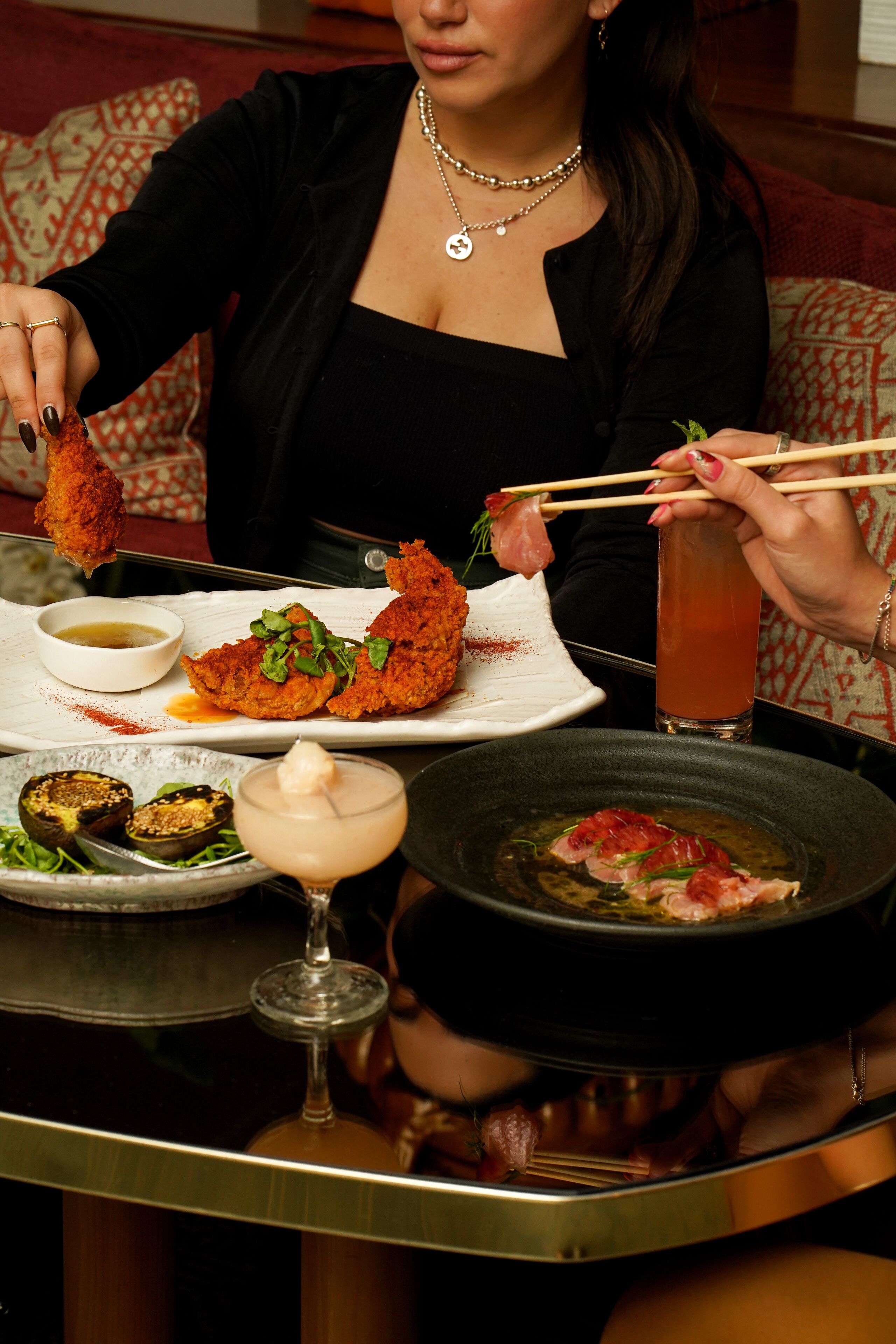 A dining table with various dishes, including a plate with fried items, a bowl of sauce, and a glass of iced tea.