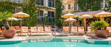 Una piscina al aire libre, camas de piscina con cargo, sombrillas