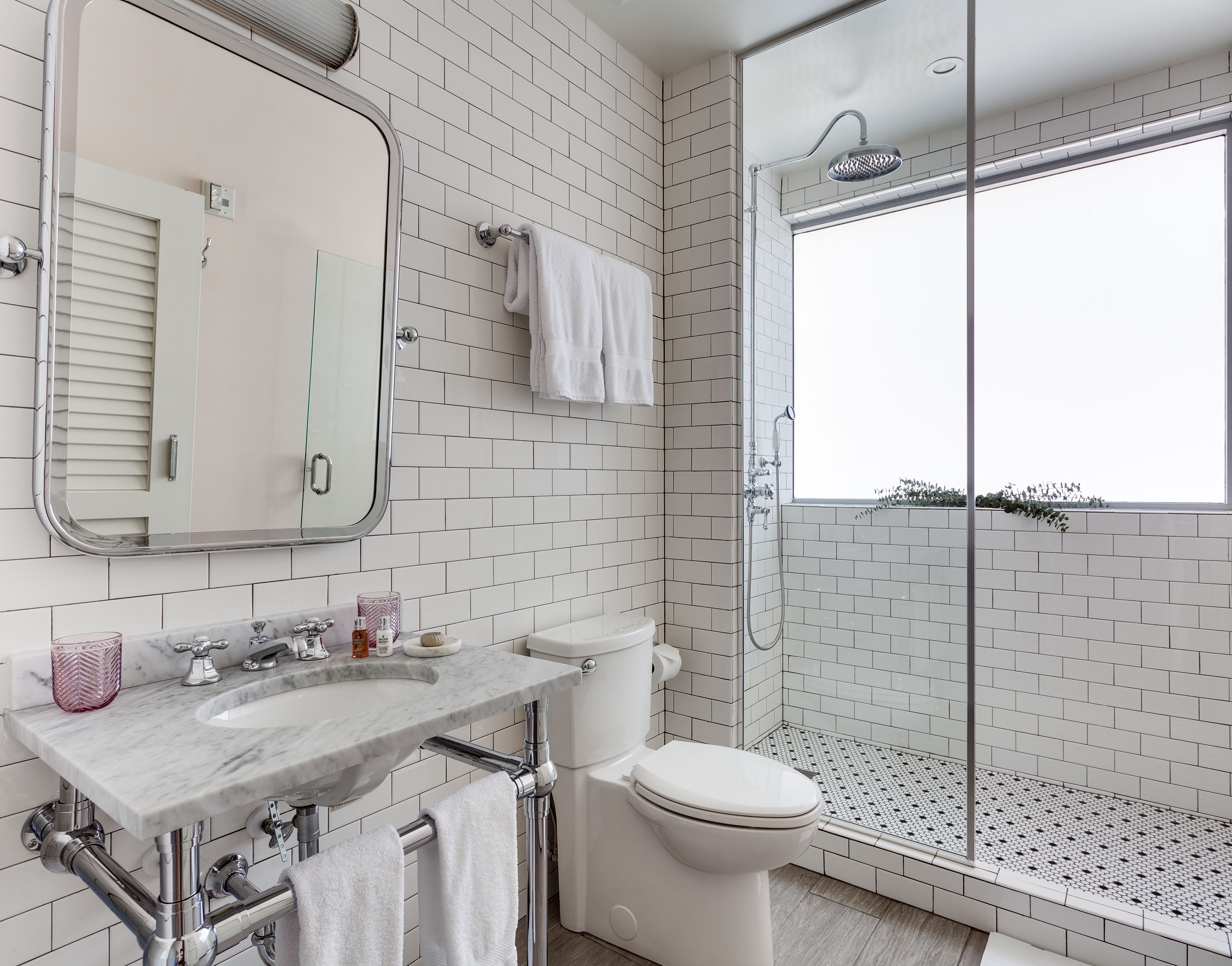 A modern bathroom with a marble sink, white toilet, and a glass-enclosed shower.