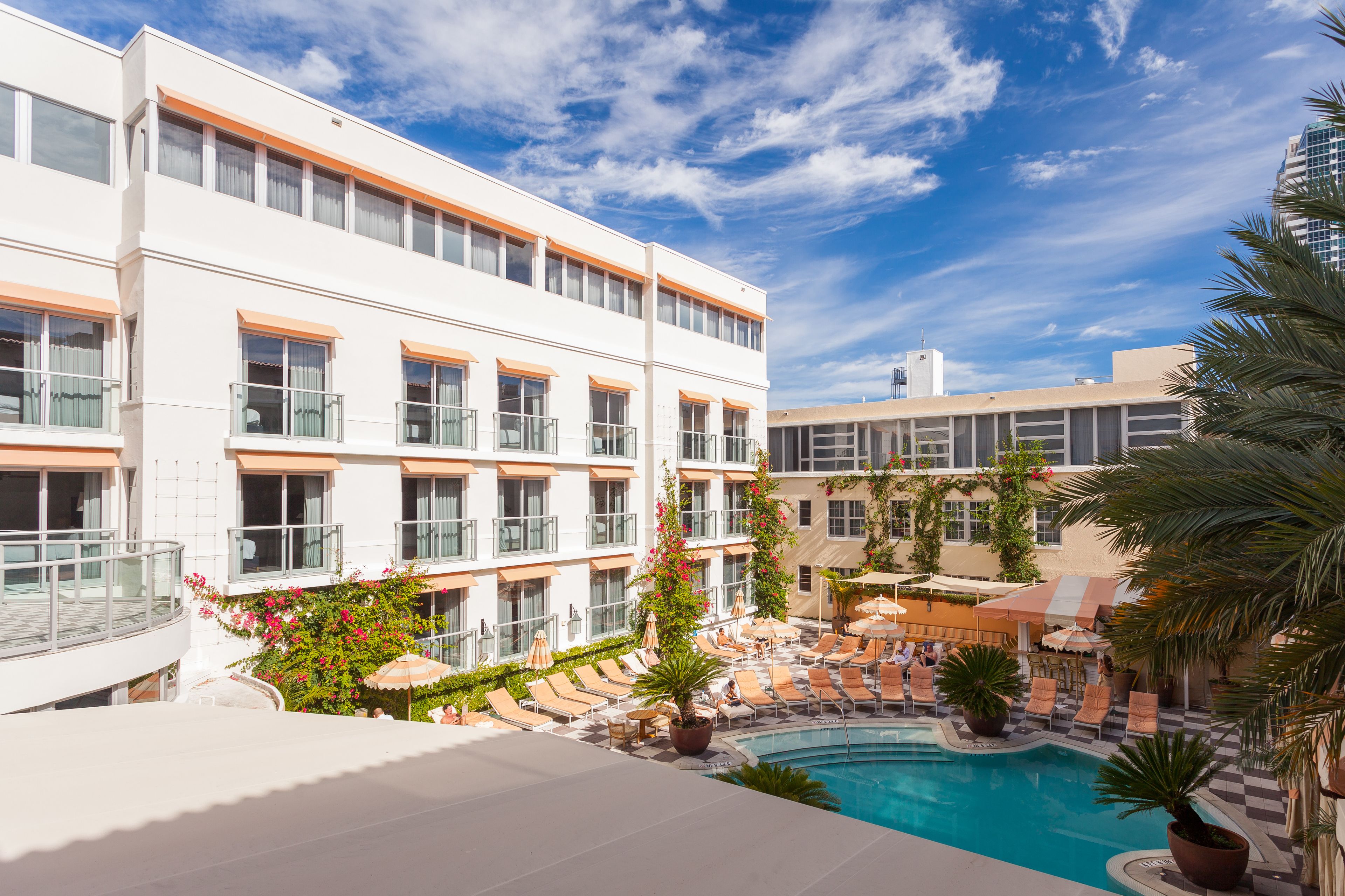 Un hotel con piscina, varios balcones y mobiliario exterior.