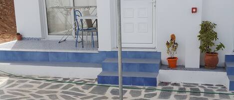 A patio area with a stone floor, a white table, and a blue canopy.